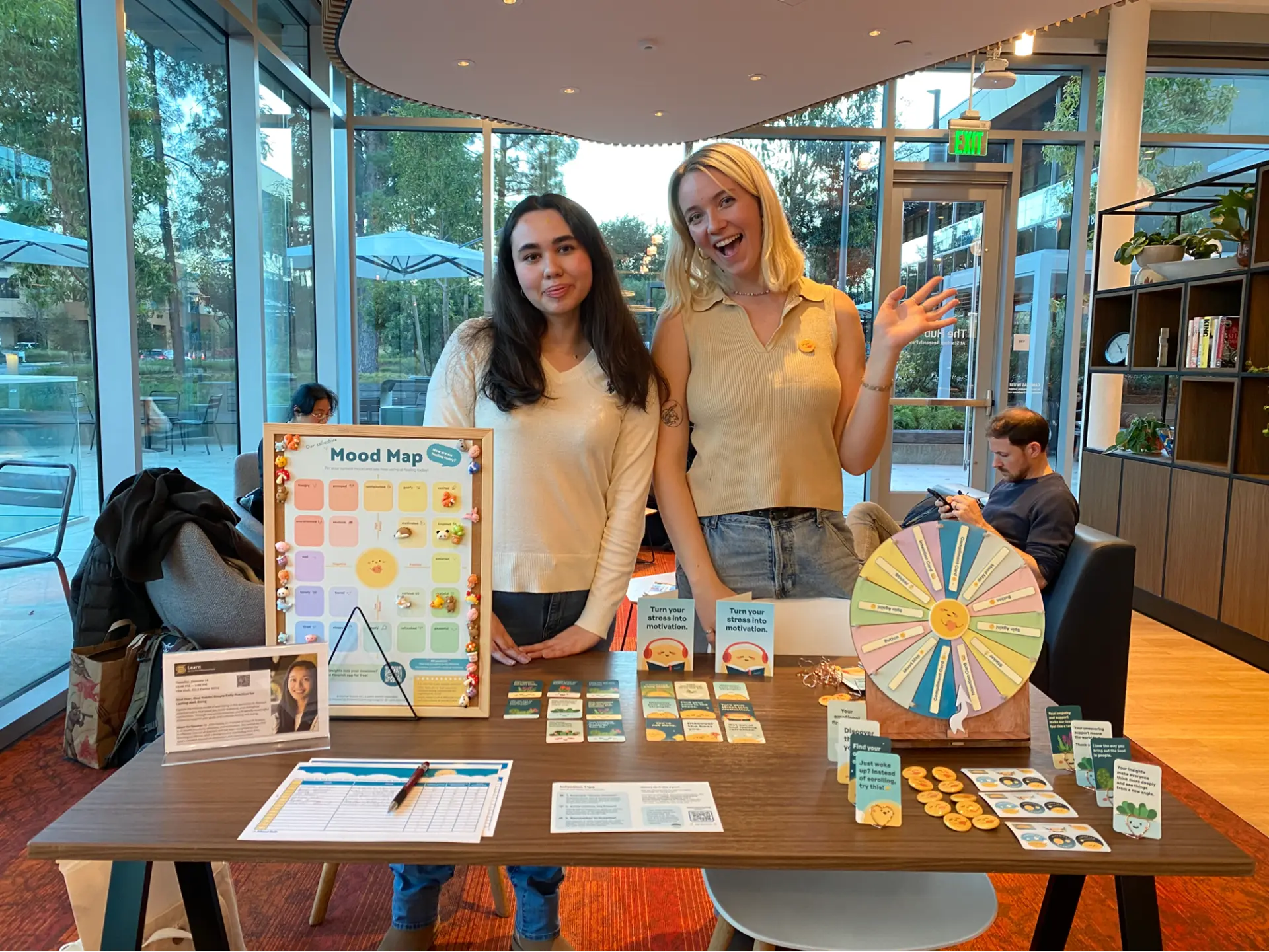 Peer wellness educators at a Flourish workshop table with the Mood Map, compliment cards, and well-being activities